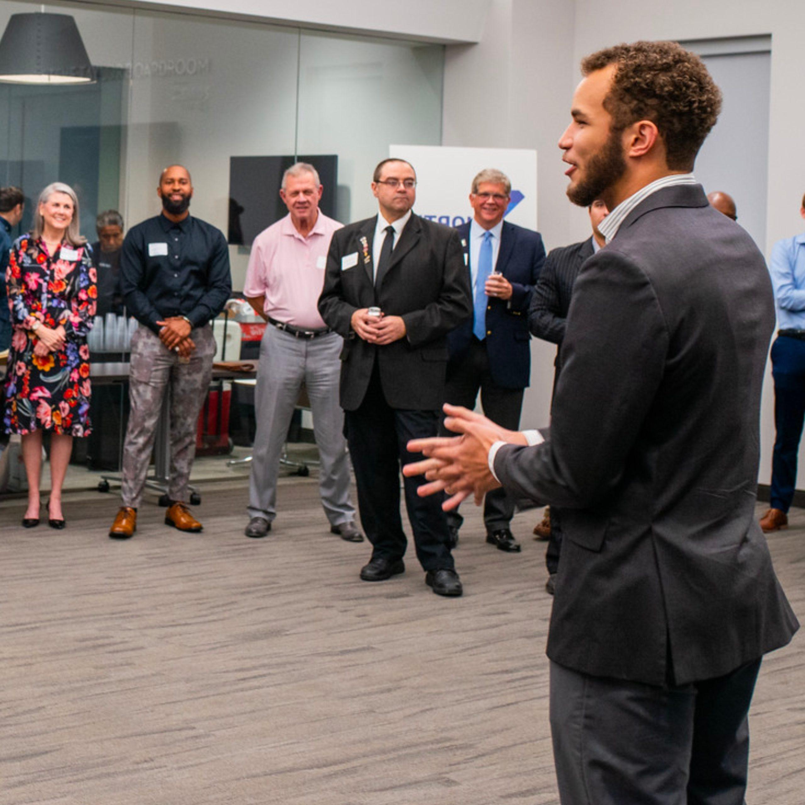 A group of people gather to listen to a person speaking.